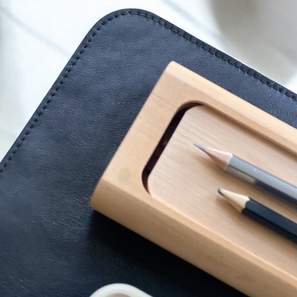 Close-up of genuine black leather desk mat showing grain texture and border stitch line"