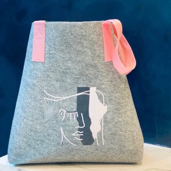 grey felt shopper bag with pink shoulder straps and abstract face print 